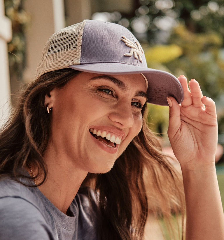Woman adjusting a lilac Signature dragon trucker cap