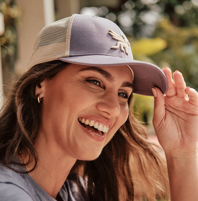 Woman adjusting a lilac Signature dragon trucker cap