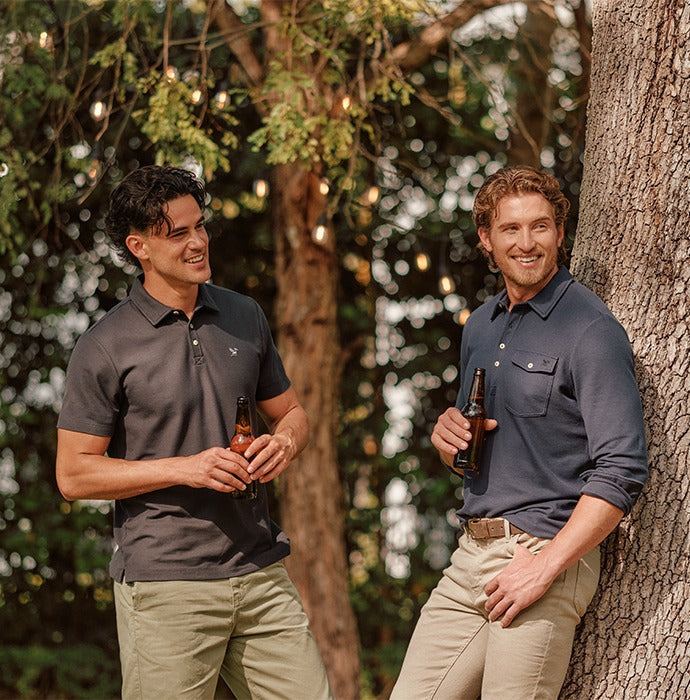 Two men in Signature pique polos talking under a tree at dusk